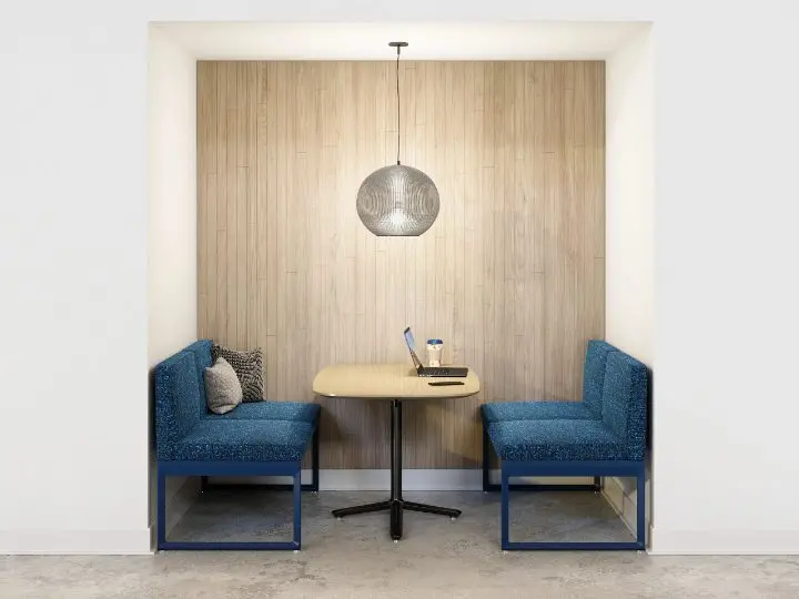 Booth-style meeting nook with Studio TK Clique benches facing a Studio TK Bevy table, set into a wood-panelled alcove with a pendant fixture overhead