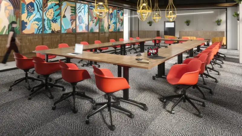 Training room rendering with a wood boardroom table and red task chairs under a mural, Anomatics